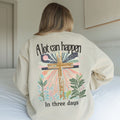 Beige sweatshirt with a cross design and text on the back, worn by a person.