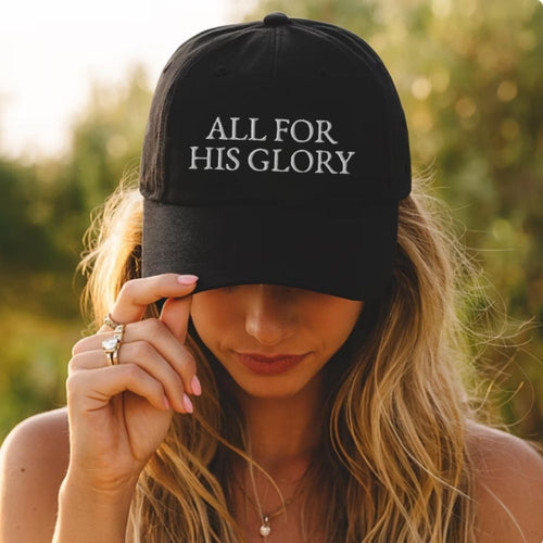 Person wearing a black cap with 'ALL FOR HIS GLORY' text outdoors.