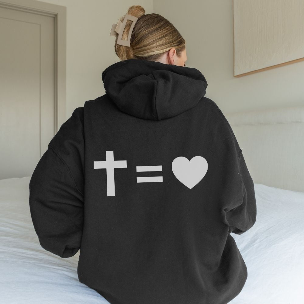 Person wearing a black hoodie with a cross, equal sign, and heart symbol on the back.