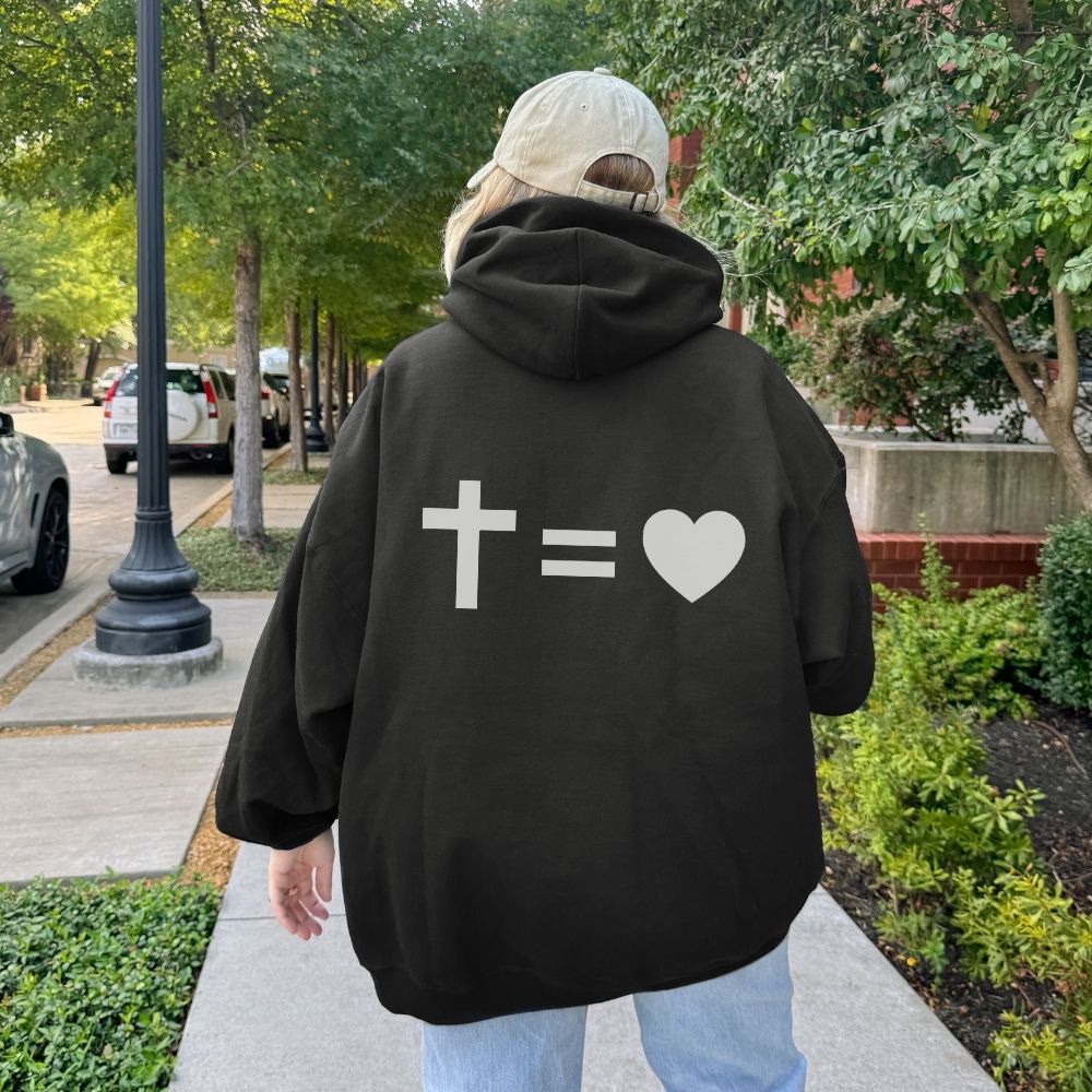 Person wearing a black hoodie with a mathematical symbol design on the back, walking outdoors.