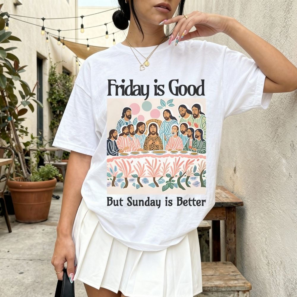 Person wearing a white t-shirt with a graphic and text 'Friday is Good But Sunday is Better' outdoors.