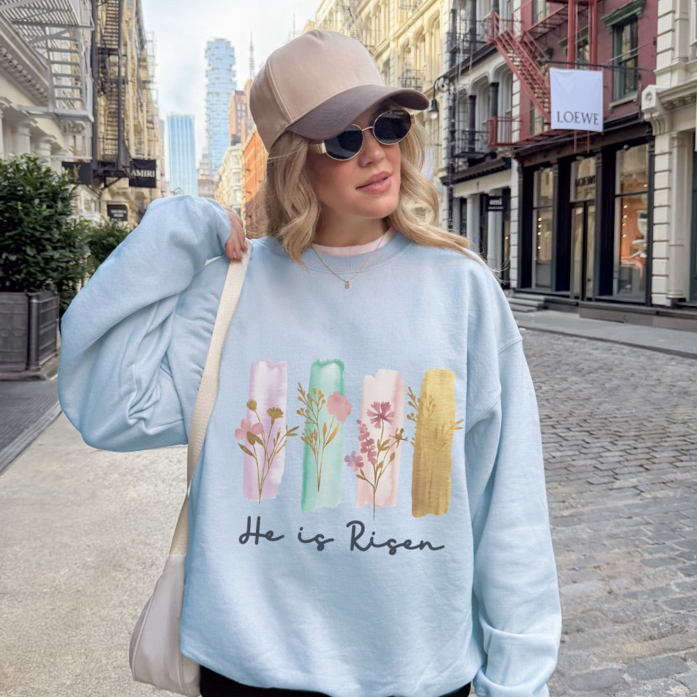 Woman wearing a light blue sweatshirt with floral designs and text, standing on a city street.