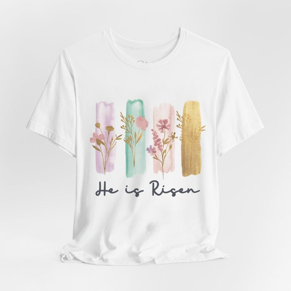 White t-shirt with floral design and 'He is Risen' text on a white background