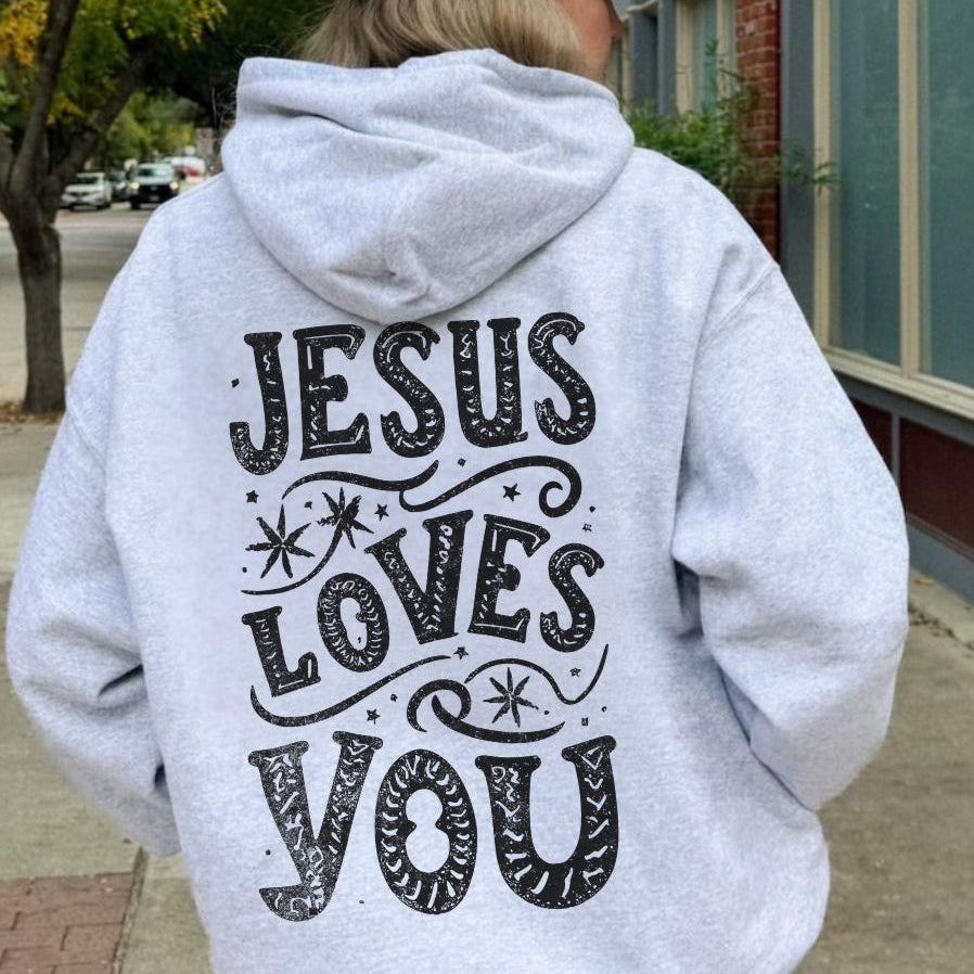 Model wearing a light grey hoodie with the text “Jesus Loves You” on the back