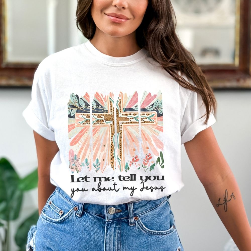 Person wearing a white t-shirt with a colorful cross design and text.