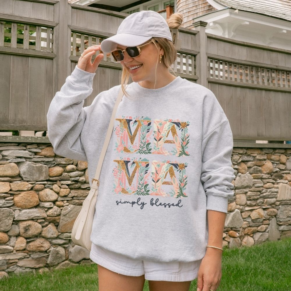 Woman wearing a gray sweatshirt with floral text design outdoors.