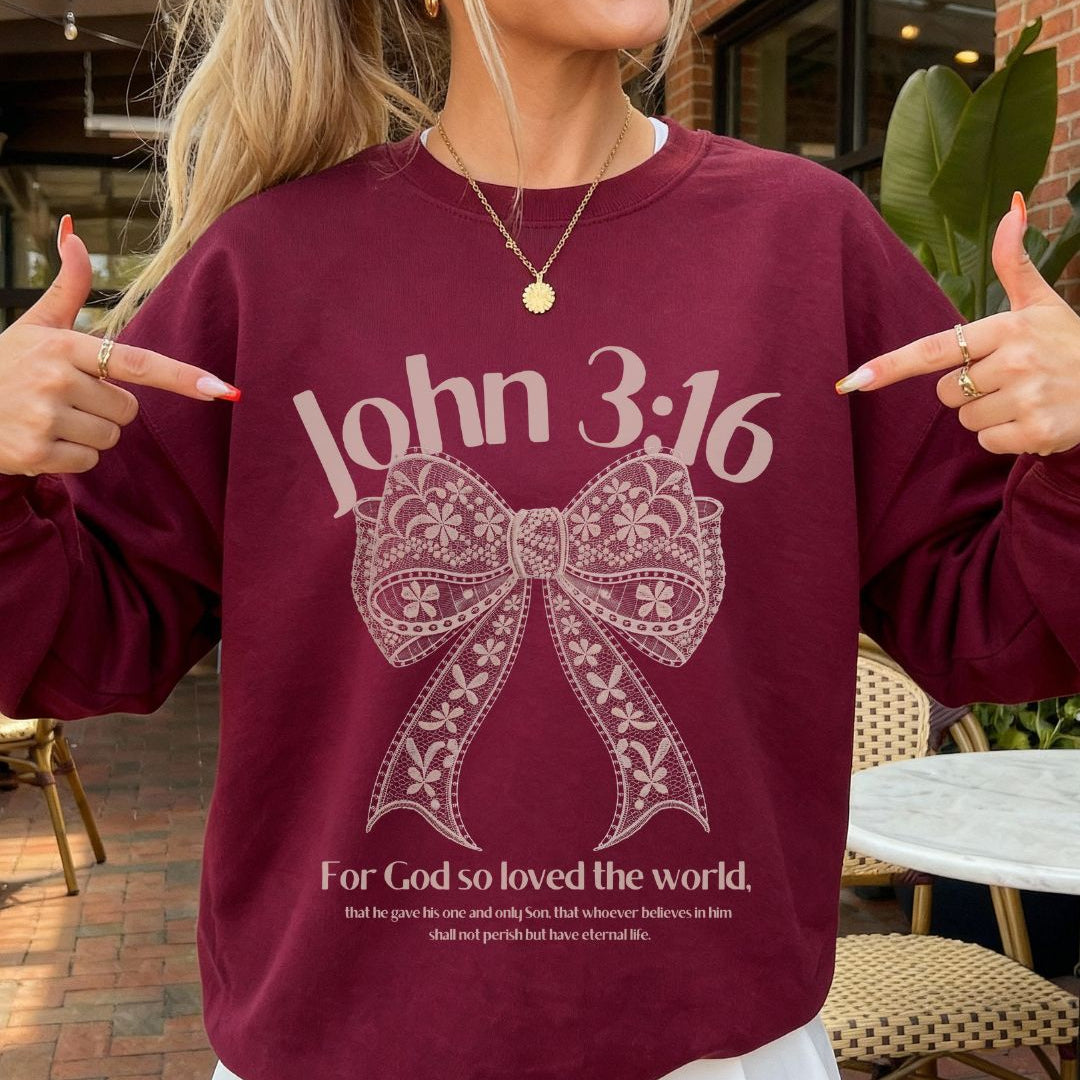Person wearing a maroon sweatshirt with 'John 3:16' text and a bow graphic, pointing at the text.