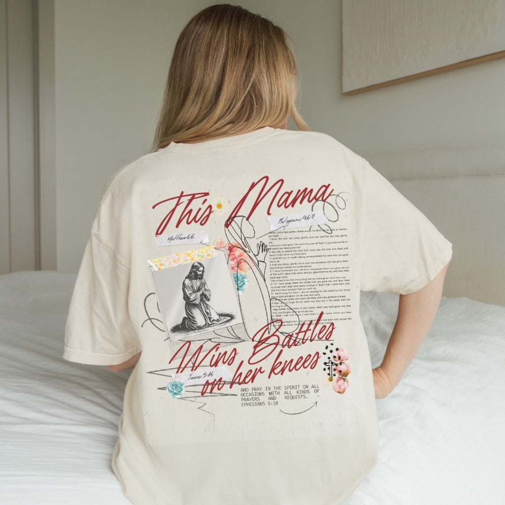 Person wearing a t-shirt with a graphic design on the back, sitting on a bed.