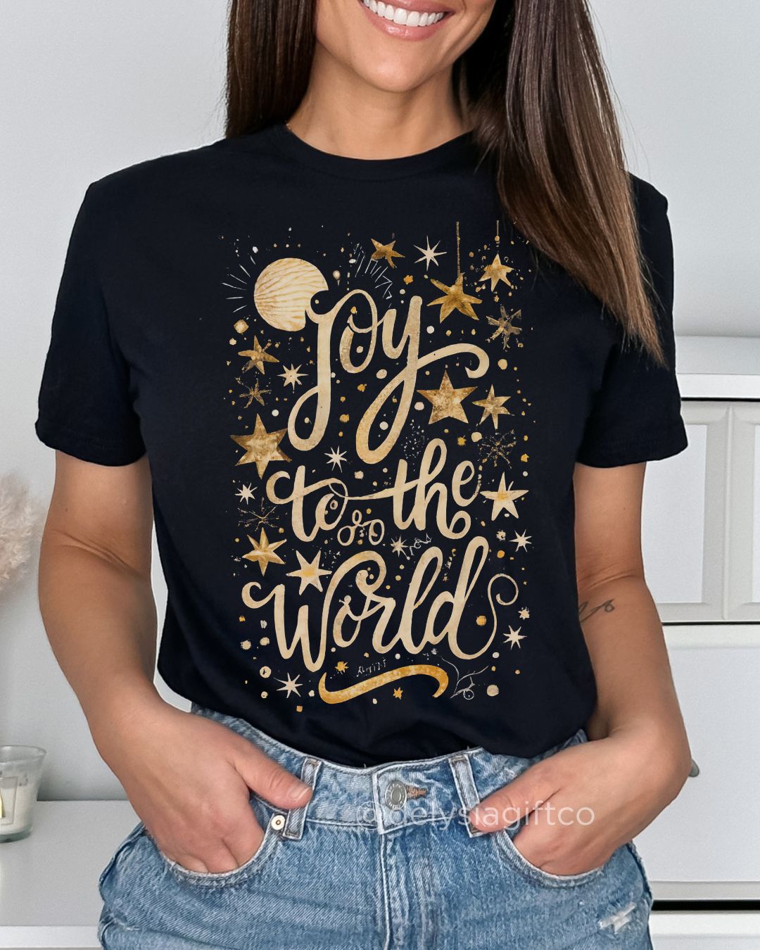Woman wearing Joy to the World Christian T-shirt — gold star design celebrating Jesus and faith-based Christmas joy.
