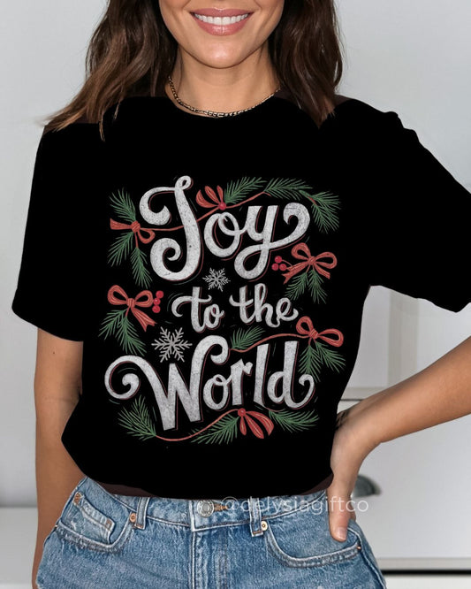 Woman wearing Joy to the World Christian Christmas T-shirt — festive faith-based design with greenery and red bows.