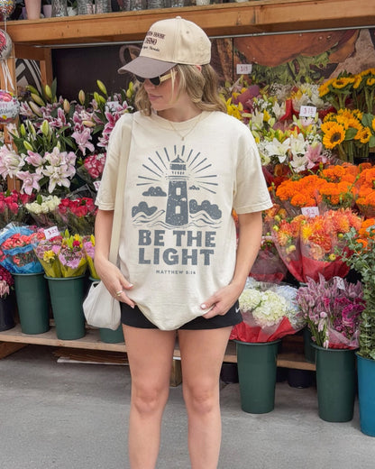 Woman wearing ivory Be the Light Christian t-shirt outdoors