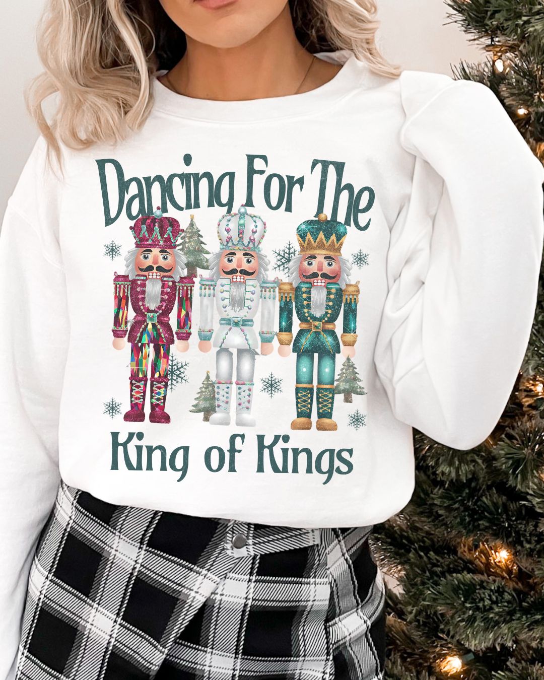 Woman wearing Dancing for the King of Kings Christian Christmas sweater with three colorful nutcracker figures.