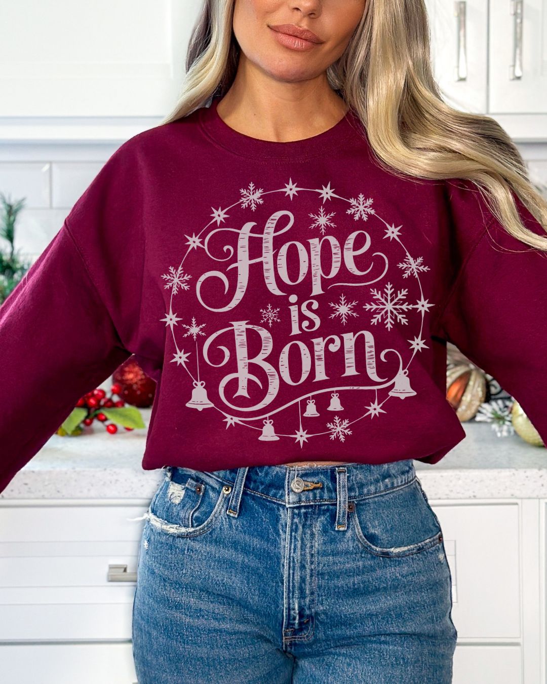 Woman wearing burgundy Hope Is Born Christian Christmas sweater with snowflake and star design.
