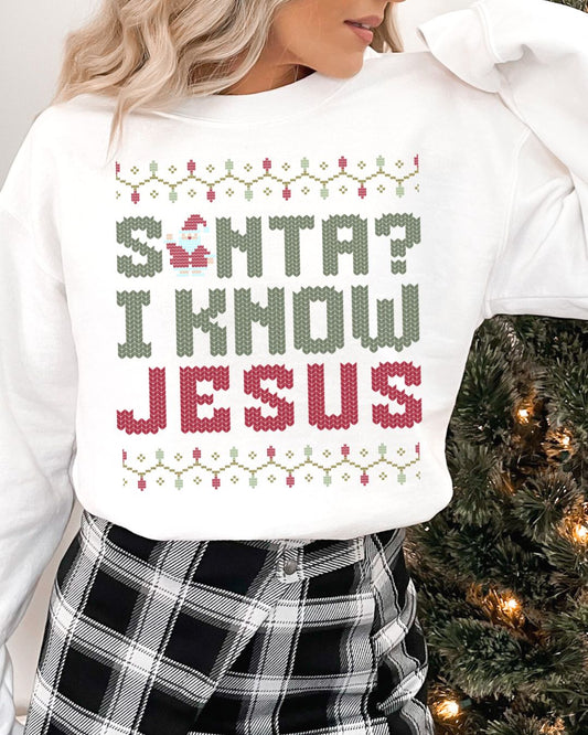Woman wearing white Christian Christmas sweater with the phrase Santa? I Know Jesus in festive cross-stitch style.